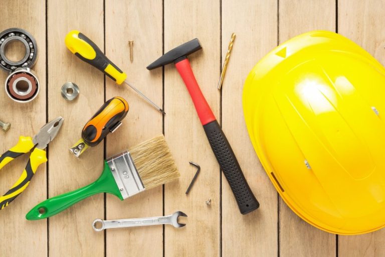 Construction tools, including a wrench and saw, scattered across a wooden floor.